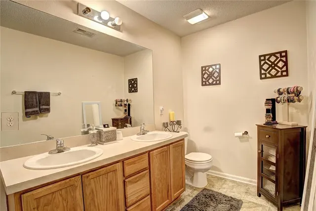 a bathroom with a double vanity sink toilet and a mirror