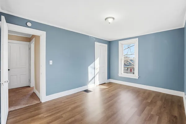 a view of an empty room with wooden floor and a window