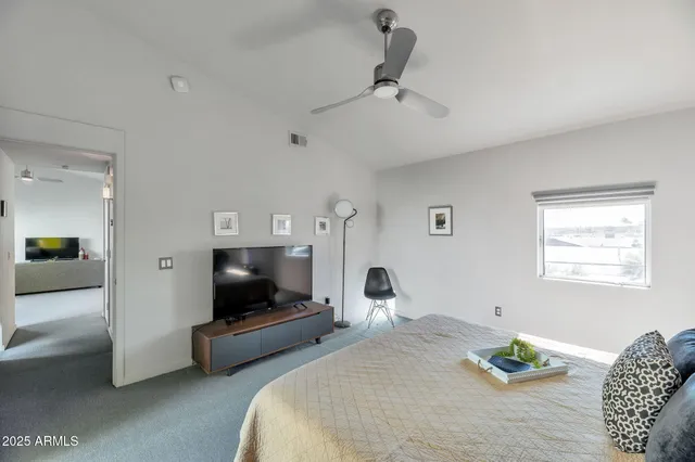 a bedroom with a bed a couch and a flat screen tv