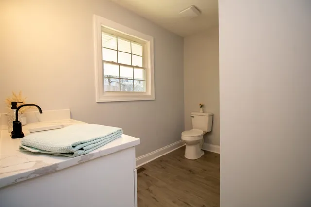 a bathroom with a granite countertop toilet a sink and a window