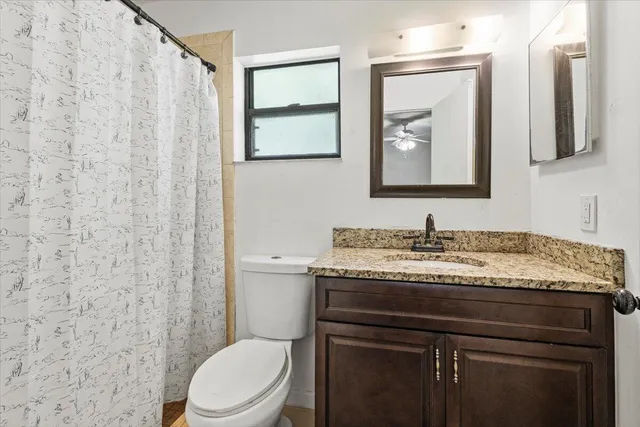 a bathroom with a granite countertop sink toilet and mirror