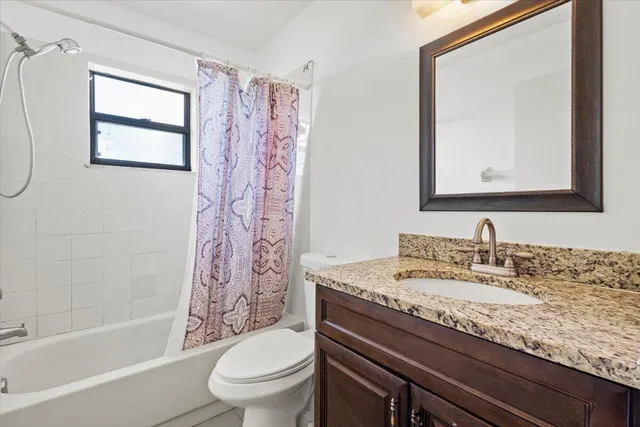 a bathroom with a granite countertop sink a toilet and a bathtub
