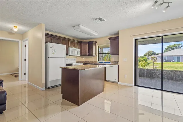 a kitchen with kitchen island a counter top space a refrigerator and a fireplace