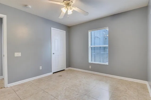 an empty room with ceiling fan and window