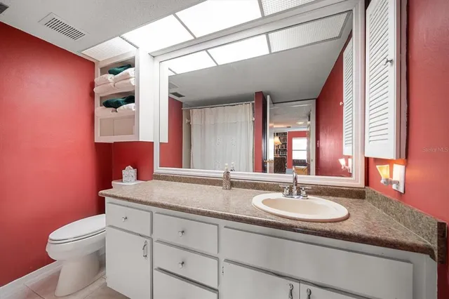 a bathroom with a granite countertop sink a toilet and mirror