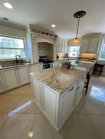 a kitchen with stainless steel appliances granite countertop a sink a stove and a wooden cabinets