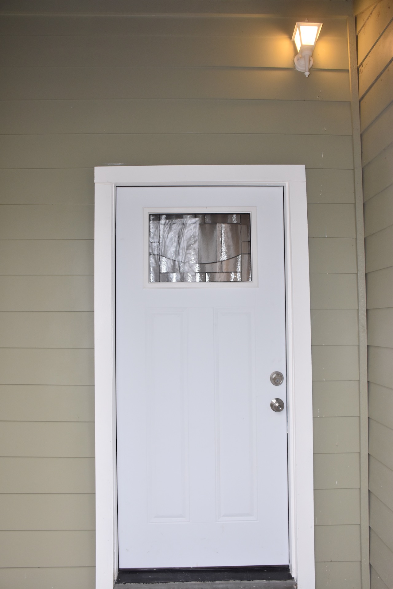 1810 Rawhide Loop Round Rock, TX 78681 - Photo 4 of 29 Front entry with a white paneled door featuring a decorative frosted glass insert, white trim, and a wall-mounted exterior light fixture