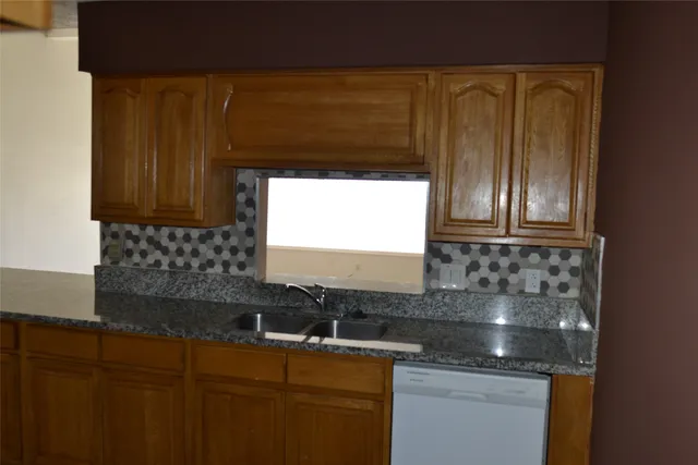 a kitchen with granite countertop wood cabinets and a sink