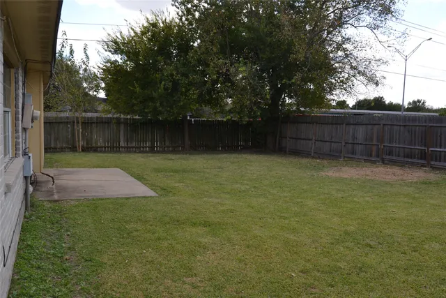 a view of a backyard with a fence and trees
