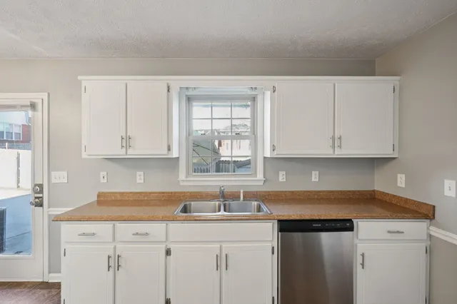 a kitchen with granite countertop white cabinets and sink