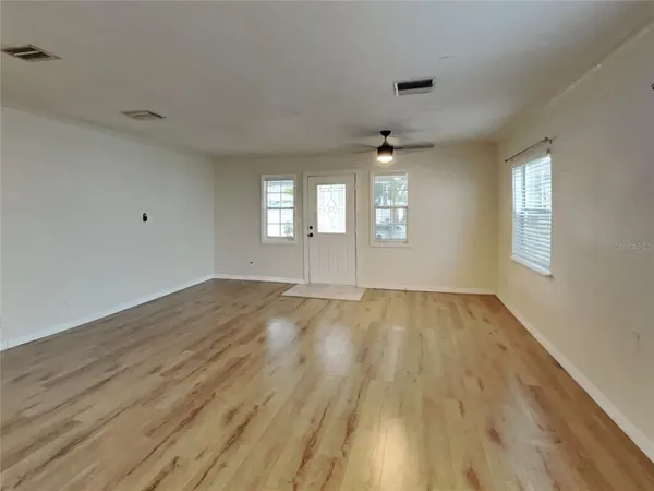 an empty room with wooden floor and windows