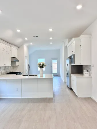a large kitchen with stainless steel appliances a large counter top a stove and a refrigerator