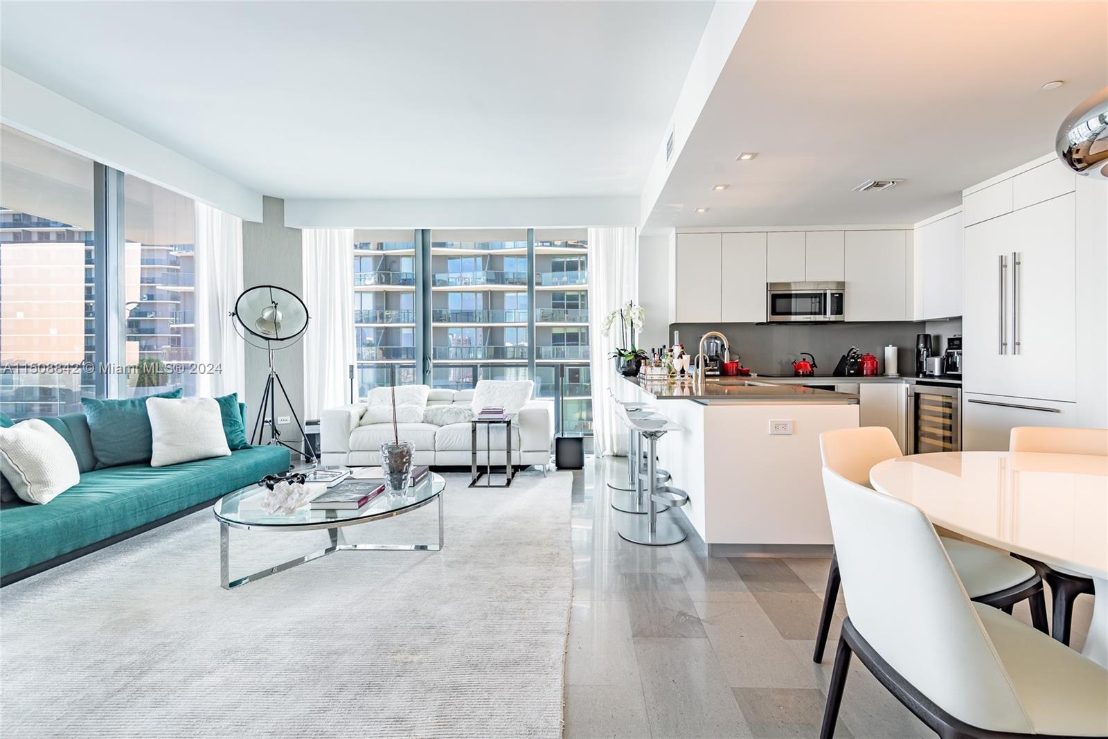 a living room with furniture and a large window with kitchen view