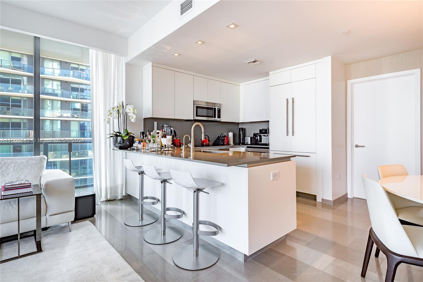 88 Southwest 7th Street, Unit 3301 Miami, FL 33130 - Photo 9 of 54 a kitchen with stainless steel appliances granite countertop a stove a sink a dining table and chairs with white cabinets