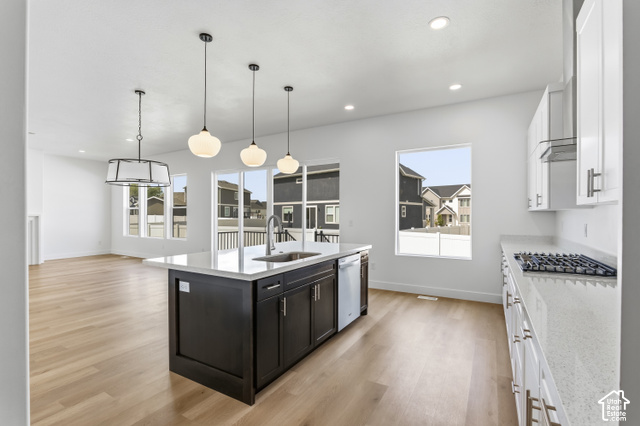 79 South Crimson Way West, Unit 307 Mapleton, UT 84664 - Photo 20 of 42 Spacious open-concept living area featuring wood-finish flooring, a kitchen island with pendant lighting, white cabinetry, integrated stainless steel appliances, and a gas cooktop