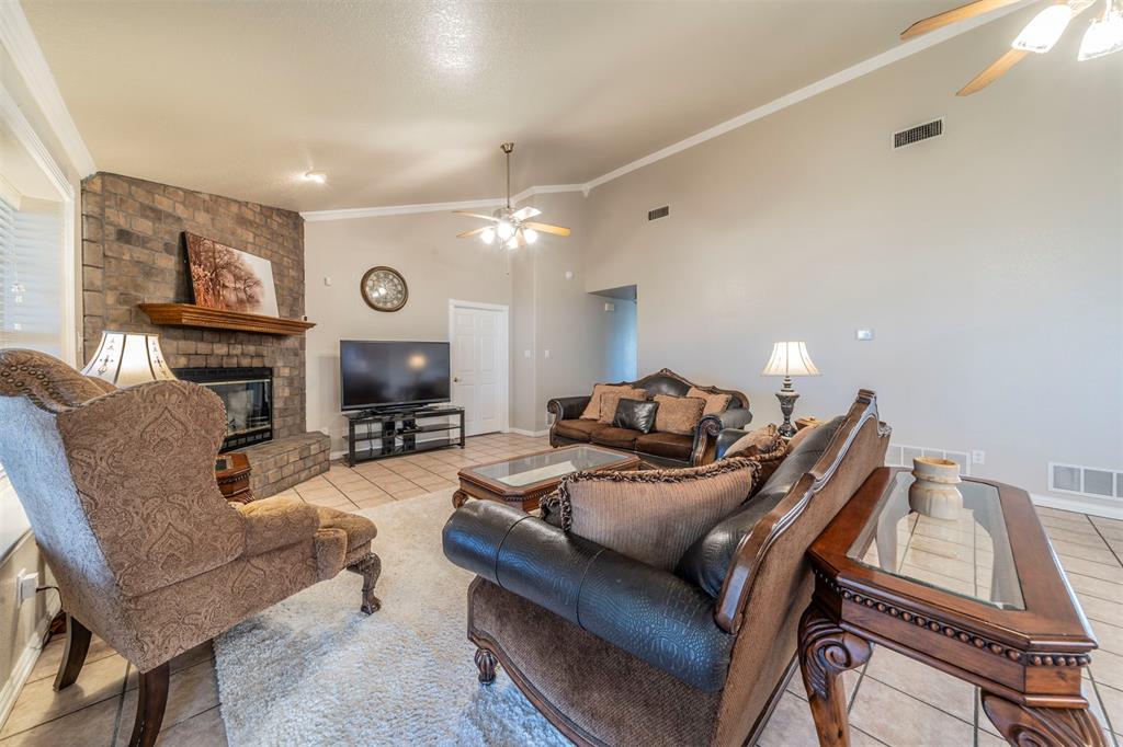 20175 Willow Glade Circle Pilot Point, TX 76258 - Photo 5 of 32 Living room featuring high vaulted ceiling, crown molding, a brick fireplace, ceiling fan, and light tile patterned floors