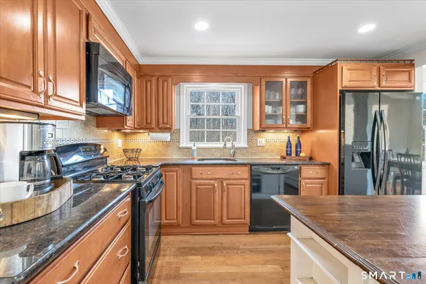 a kitchen with stainless steel appliances granite countertop hardwood floor sink stove and granite counter top