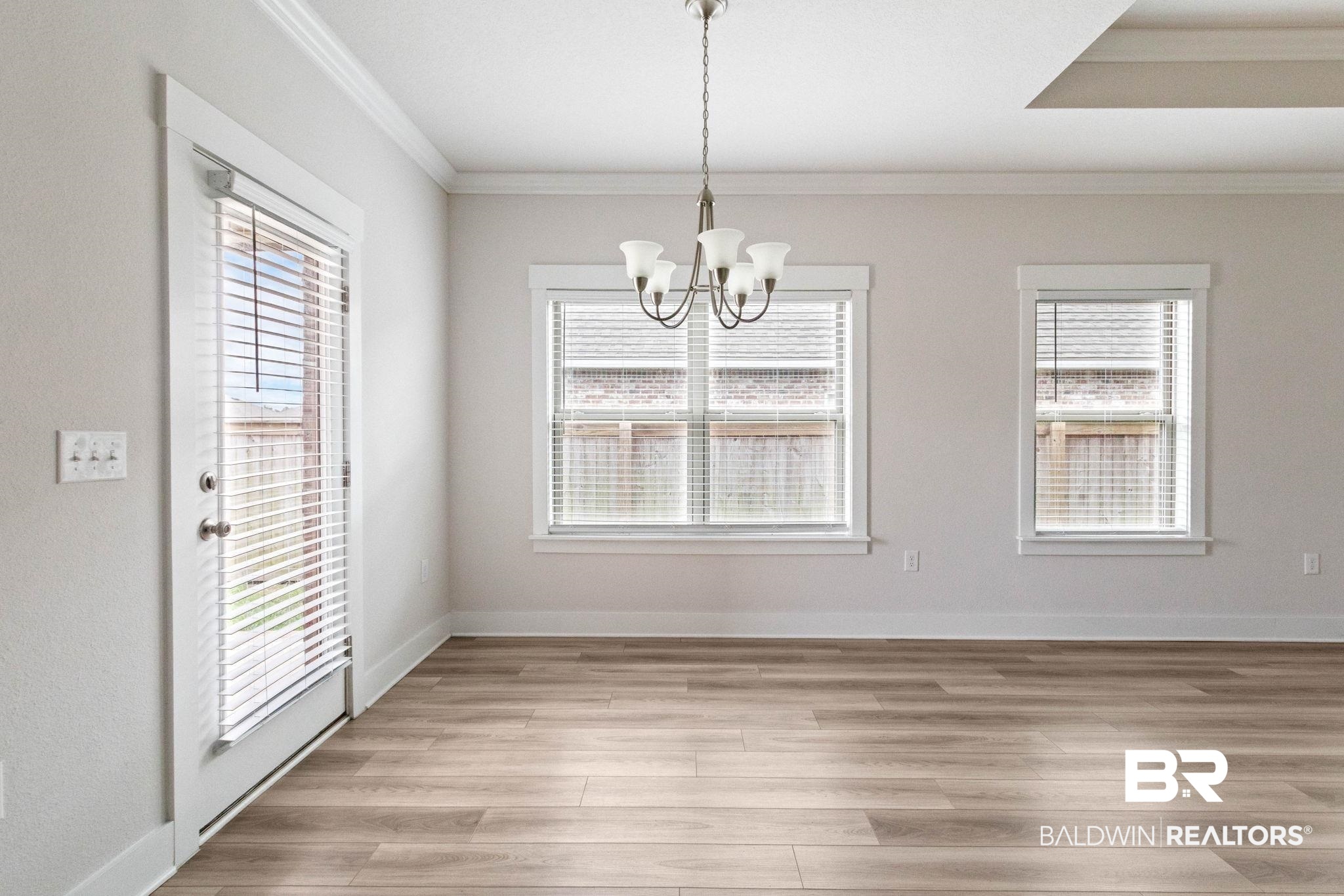 1710 Grouse Street Foley, AL 36535 - Photo 34 of 76 Spacious interior featuring wood-finish flooring, two windows with blinds, a full-light door with blinds, crown molding, and a tray ceiling