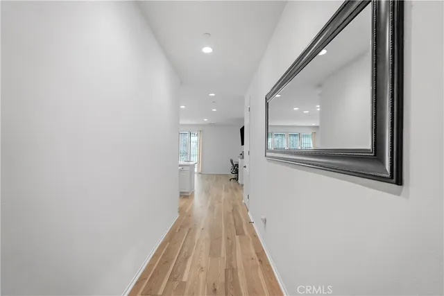 a view of a hallway with wooden floor and a bathroom