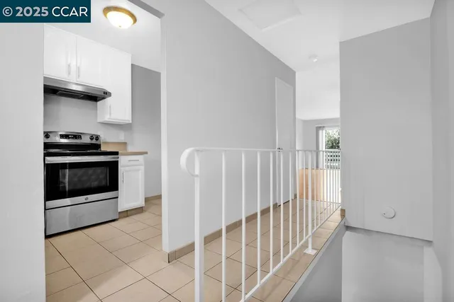 a view of a kitchen with an empty room and wooden floor