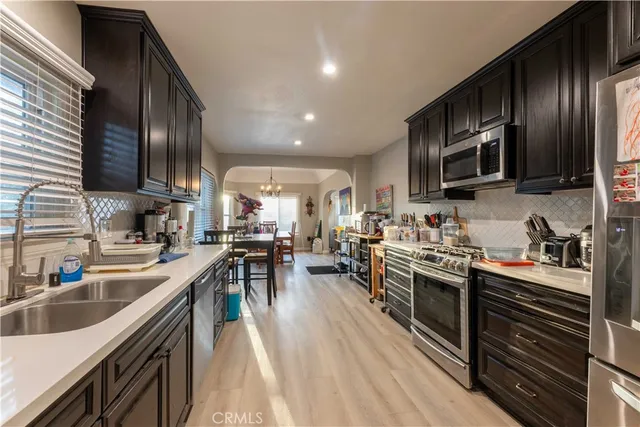 a kitchen with stainless steel appliances granite countertop a stove top oven a sink dishwasher a refrigerator and cabinets with wooden floor