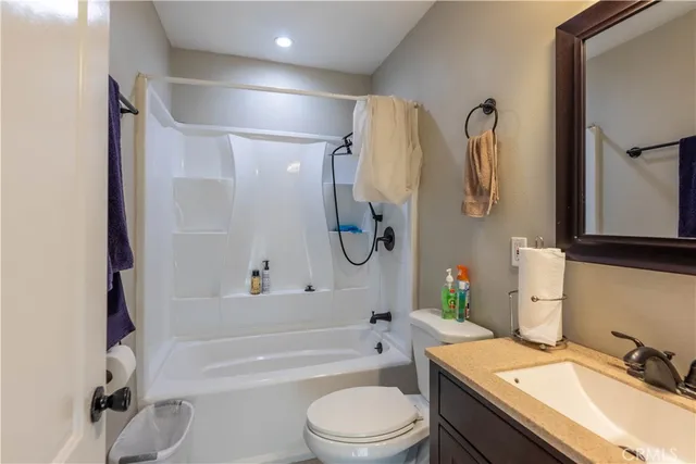a bathroom with a granite countertop bathtub shower sink mirror vanity and toilet