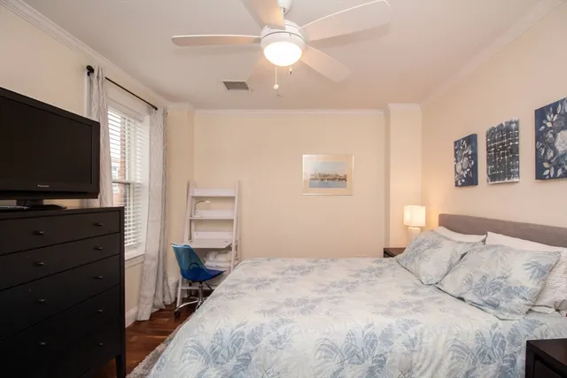 a bedroom with a bed and a flat tv screen on dresser