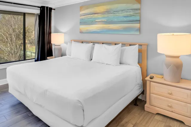 a large bedroom with a bed and a flat tv screen on dresser