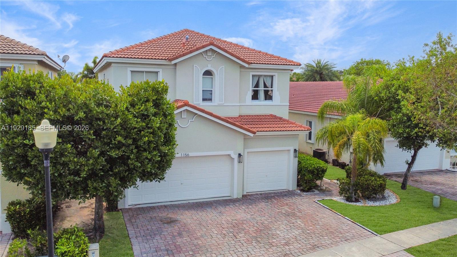 1156 Northeast 37th Place Homestead, FL 33033 - Photo 28 of 35 a white house with a small yard plants and a large tree