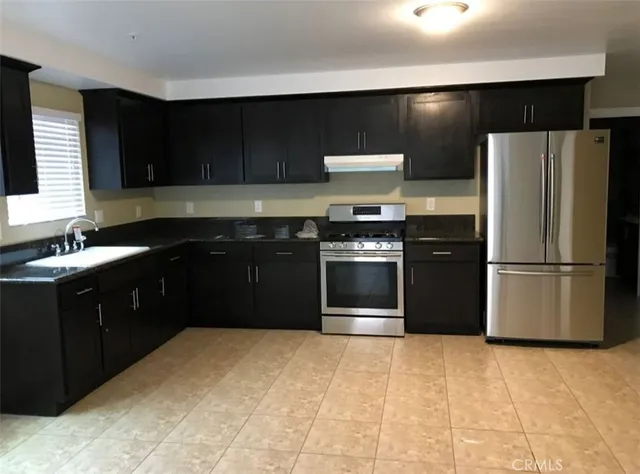 a kitchen with stainless steel appliances granite countertop a refrigerator and a stove