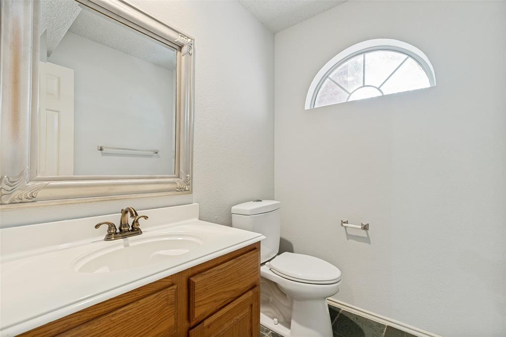 1215 Spring Creek Drive Allen, TX 75002 - Photo 18 of 40 Bathroom featuring a wood-finish vanity with an integrated sink, a decorative framed mirror, and a toilet