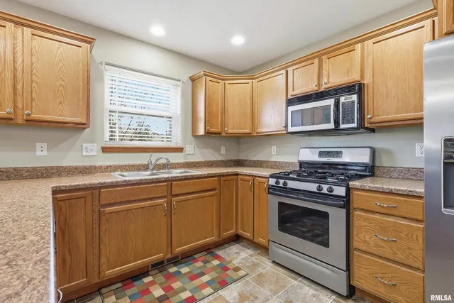 a kitchen with stainless steel appliances granite countertop a stove a sink and a microwave