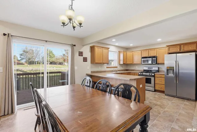 a kitchen with granite countertop a stove a refrigerator and a dining table