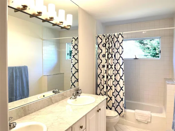 a bathroom with a sink a toilet a mirror and shower