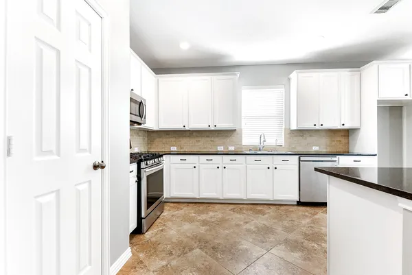 a kitchen with stainless steel appliances granite countertop a stove a sink and a refrigerator