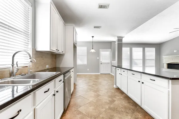 a large kitchen with granite countertop a sink and white cabinets