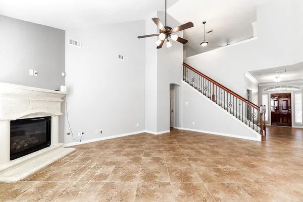 a view of an empty room with chandelier fan and fire place