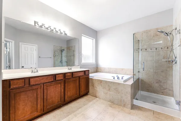 a spacious bathroom with a tub a double vanity sink a mirror and a shower
