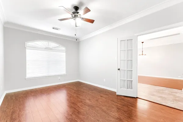 a view of an empty room with wooden floor and a window