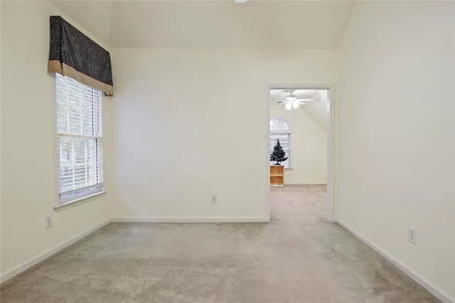 an empty room with a chandelier fan and wooden floor