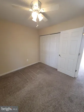an empty room with a chandelier fan and windows