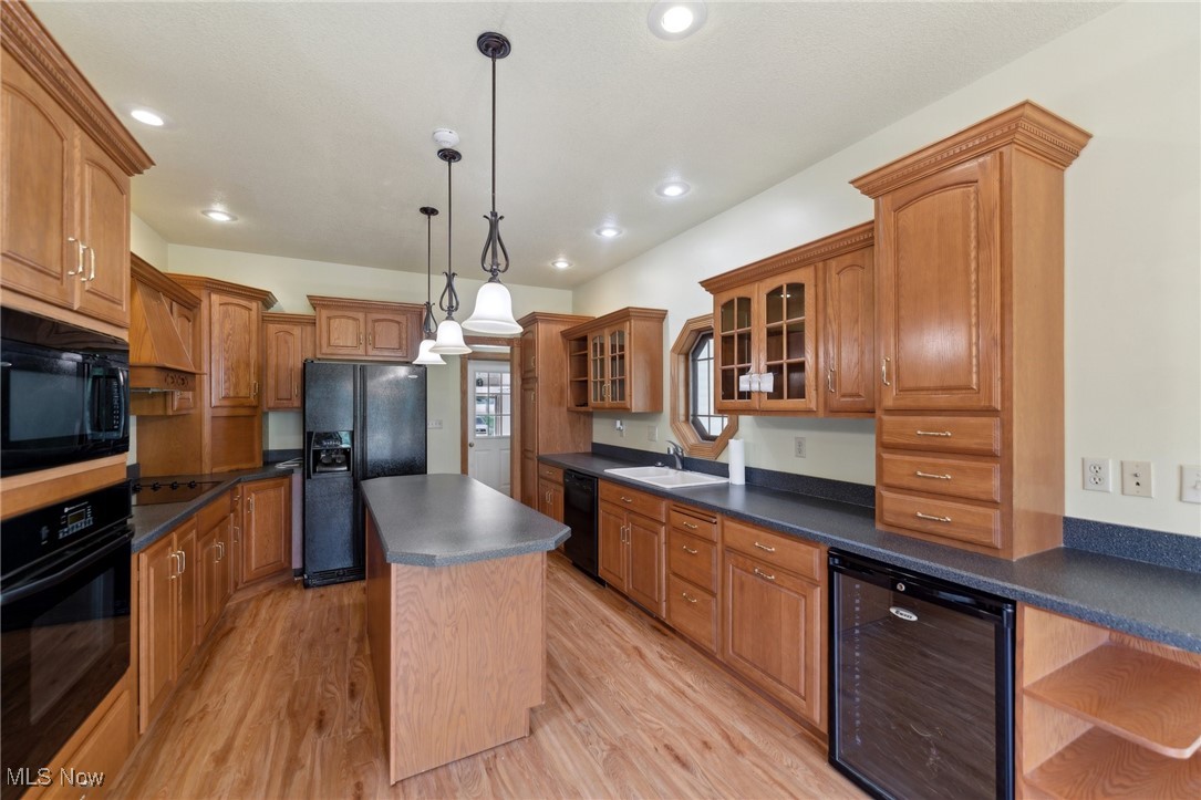 45230 Cemetery Road Wellington, OH 44090 - Photo 8 of 50 Kitchen with black appliances, beverage cooler, dark countertops, a center island, and light wood finished floors