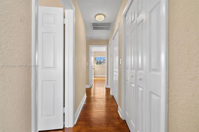 a view of an empty room with a window and wooden floor