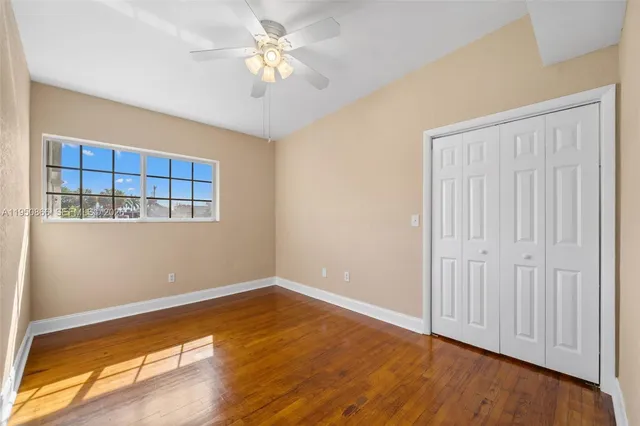 an empty room with wooden floor and a ceiling fan
