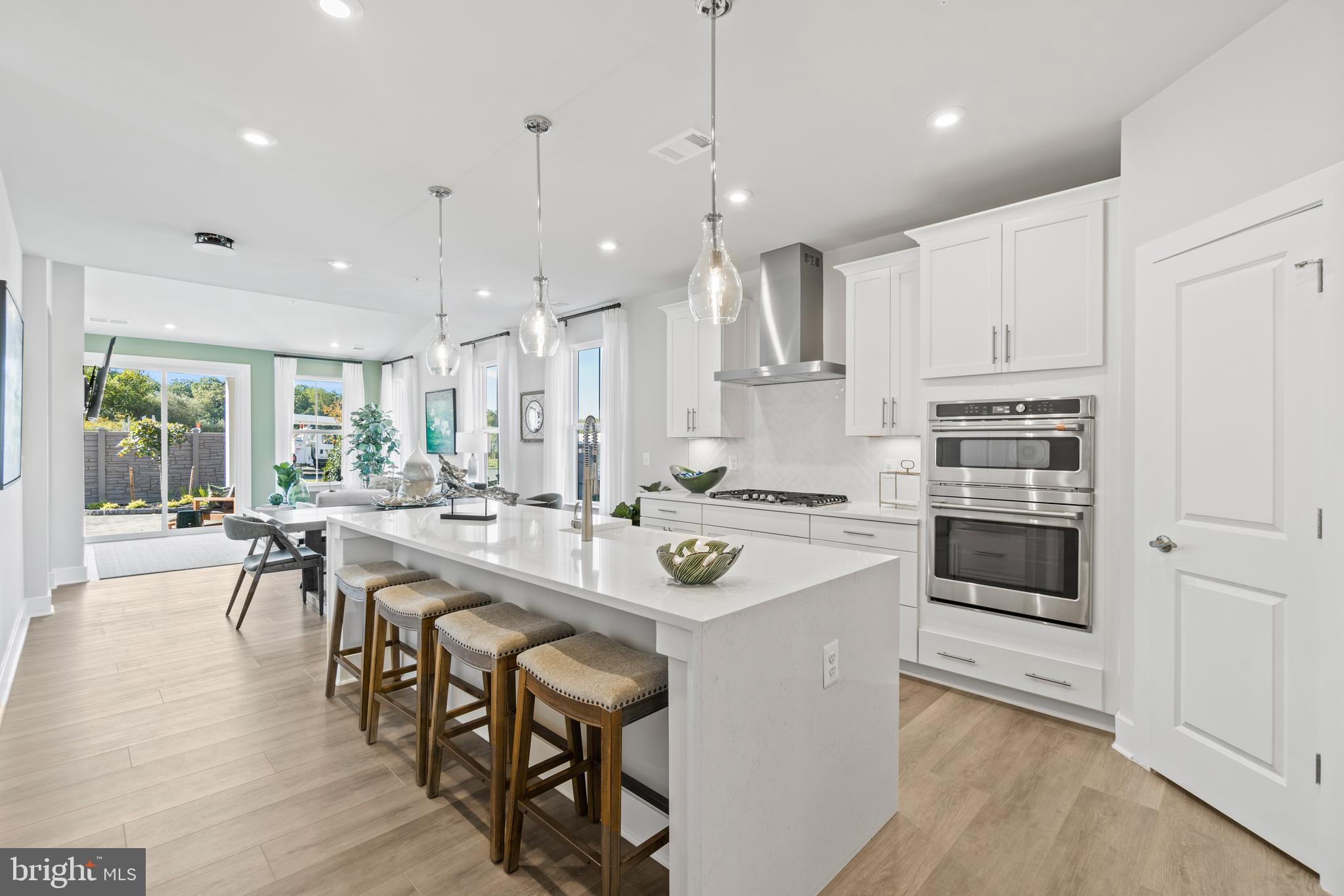 a kitchen with stainless steel appliances granite countertop a table chairs stove and white cabinets