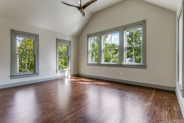 a view of an empty room with wooden floor and windows