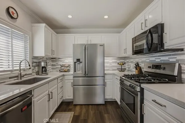 a kitchen with stainless steel appliances a refrigerator stove and white cabinets