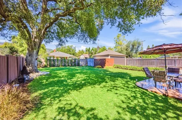a view of backyard with table and chairs and a large tree