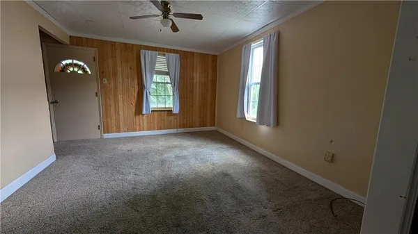 an empty room with windows and ceiling fan