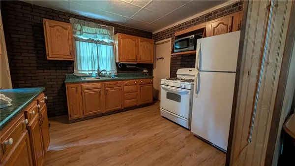 a kitchen with stainless steel appliances granite countertop a refrigerator a sink dishwasher a stove and white countertops with wooden floor